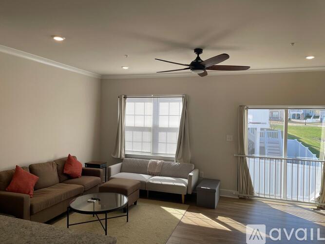 A living room with a couch, a chair, a coffee table, and a ceiling fan.