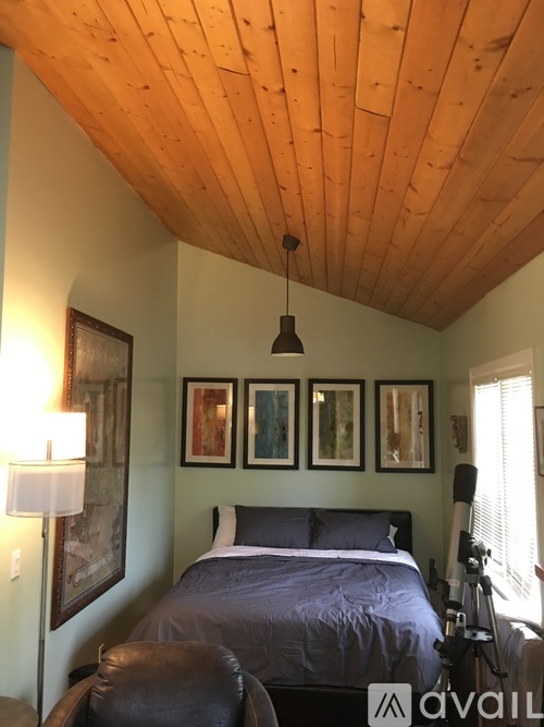 A bedroom with a bed, chair, and pictures on the wall.