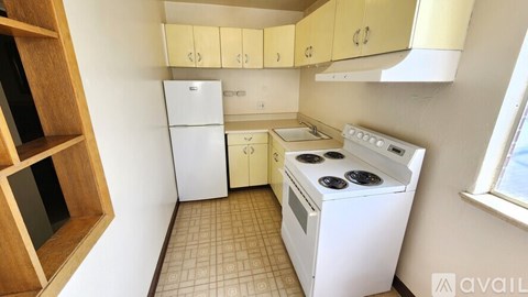 A kitchen with a white fridge, white oven, and brown cabinets.