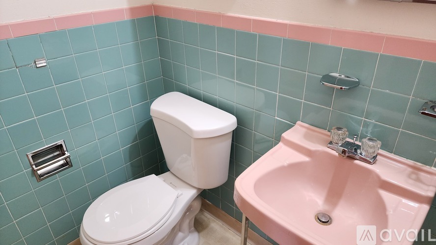 A white toilet sits next to a pink sink in a bathroom.