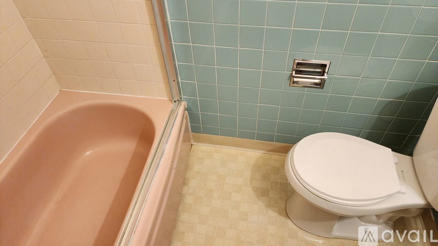 A bathroom with a pink tub and a white toilet.