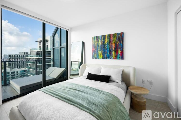 A bedroom with a large bed and a painting on the wall.