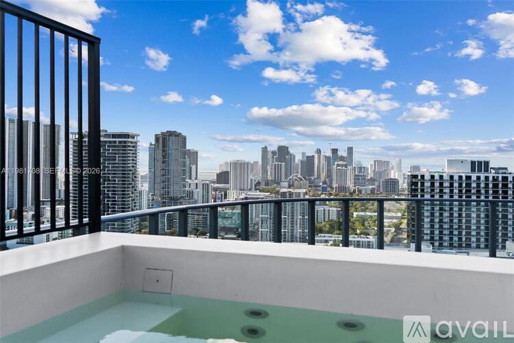 A balcony with a hot tub and a city skyline in the background.