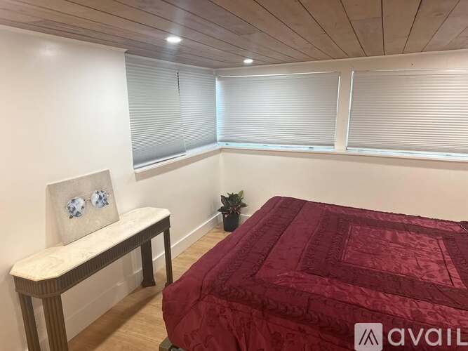 A bedroom with a bed, bench, and window with blinds.