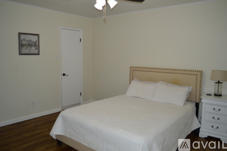 A bedroom with a bed, nightstand, and a picture on the wall.