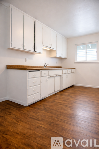 A kitchen with white cabinets and a wooden countertop.