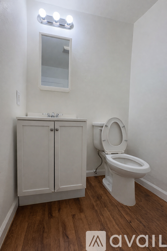 A white toilet sits next to a cabinet with a mirror above it.