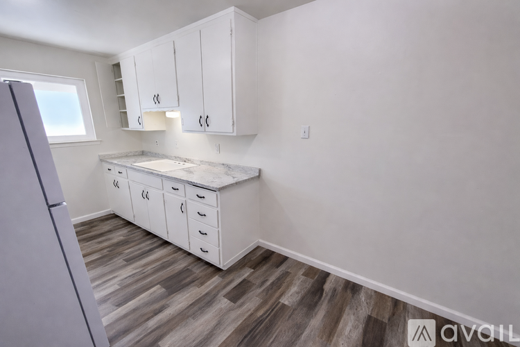 A kitchen with white cabinets and a wooden floor.
