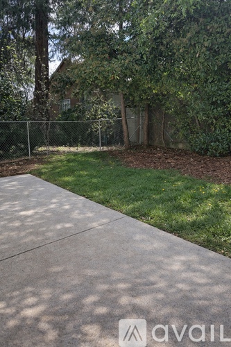 A concrete pathway leads through a grassy area with a fence and trees in the background.
