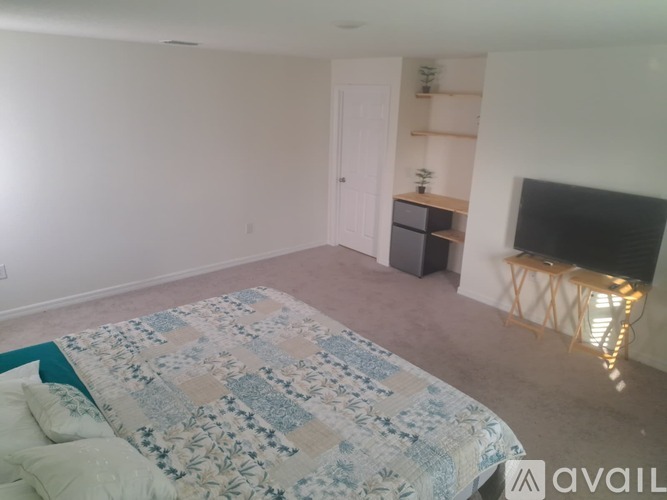 A bedroom with a bed, a TV, and a shelf.