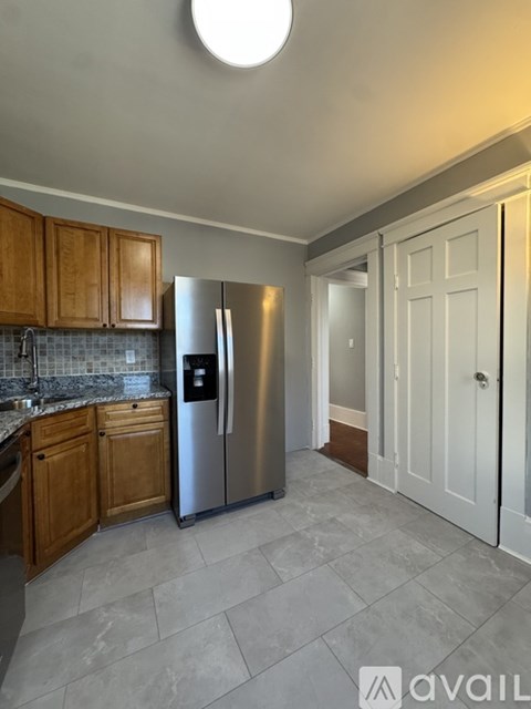 A kitchen with wooden cabinets and a stainless steel refrigerator.