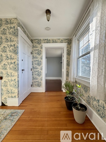 A hallway with a wooden floor and a wallpapered wall.