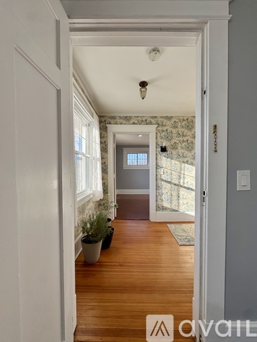A hallway with a wooden floor and a rug leading to a door.