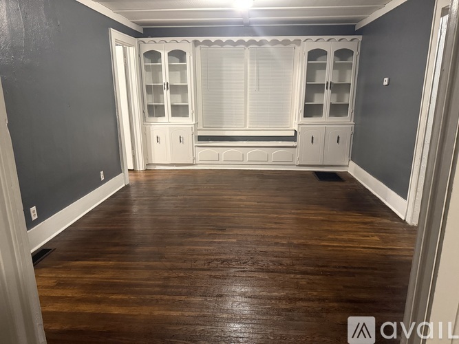 A room with wooden floors and white cabinetry.
