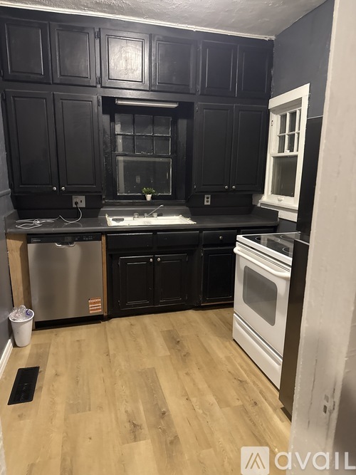 A kitchen with black cabinets and a wooden floor.