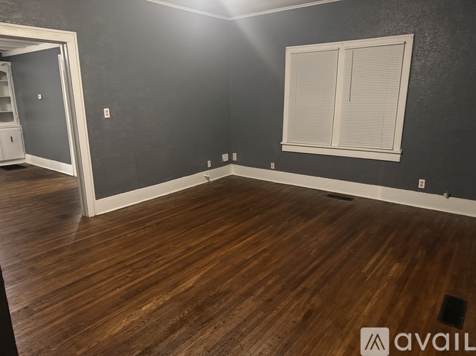 A room with wooden flooring and a window with blinds.