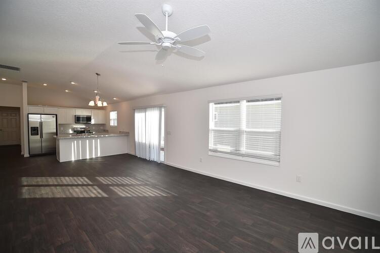 A spacious living room with a ceiling fan and hardwood flooring.