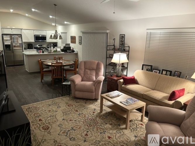 A living room with a couch, chairs, and a rug.