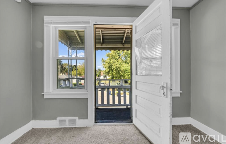 A room with a carpeted floor and a white door leading to a balcony.