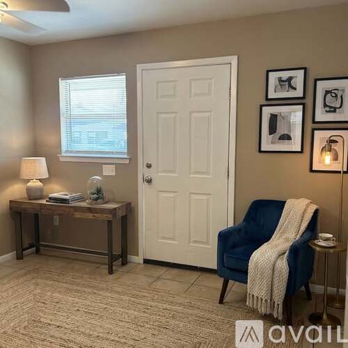 A room with a blue chair and a table with a lamp on it.