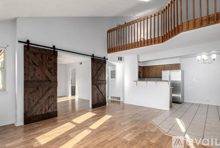 A room with a wooden floor and a white wall with a barn door.