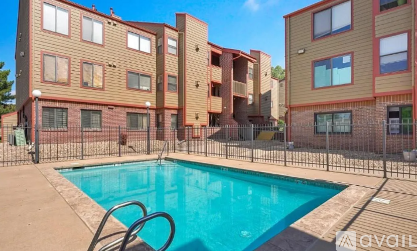 A swimming pool is surrounded by a fence and buildings.