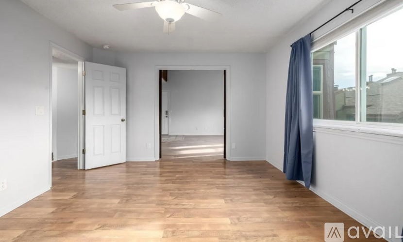 A spacious room with wooden flooring and a ceiling fan.
