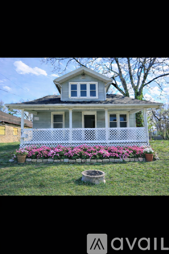 A house with a white fence and a flower bed in front.