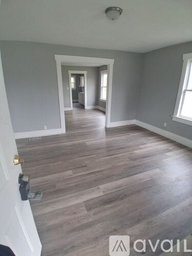 A room with wooden flooring and a door on the left.