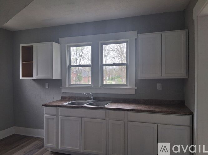 A kitchen with white cabinets and a window.