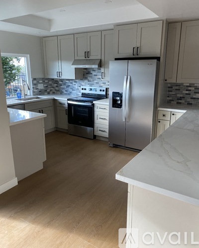 A kitchen with a refrigerator, oven, and sink.