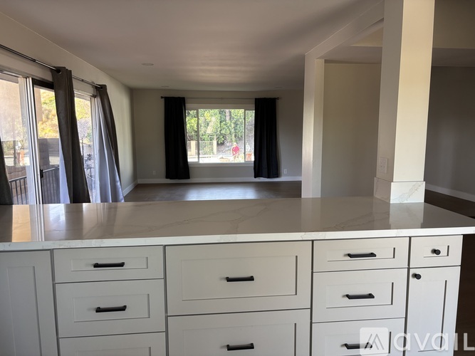 A kitchen with white cabinets and a marble countertop.