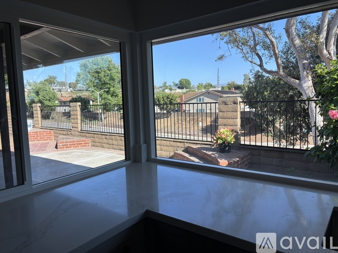 A balcony with a view of a fenced backyard and trees.
