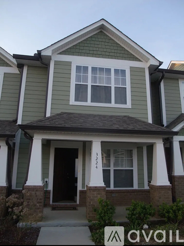 A house with a green siding and a brown roof.