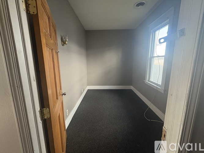 A room with a door, a window, and a carpeted floor.