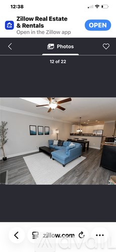 A living room with a blue couch and a ceiling fan.
