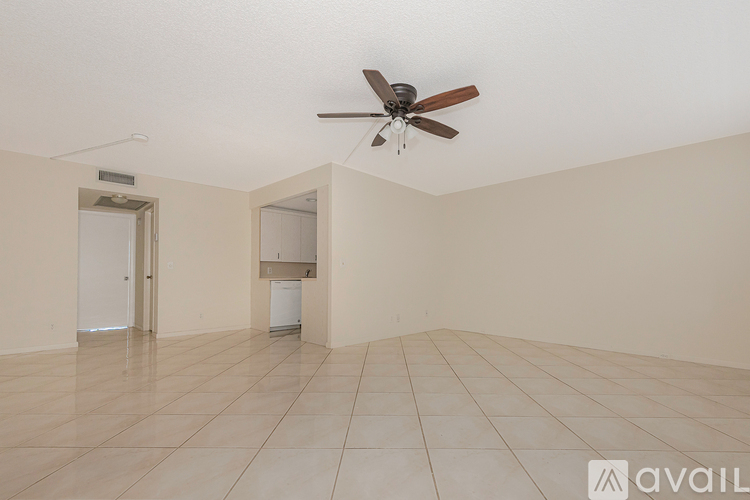 A spacious room with a ceiling fan and a white refrigerator.