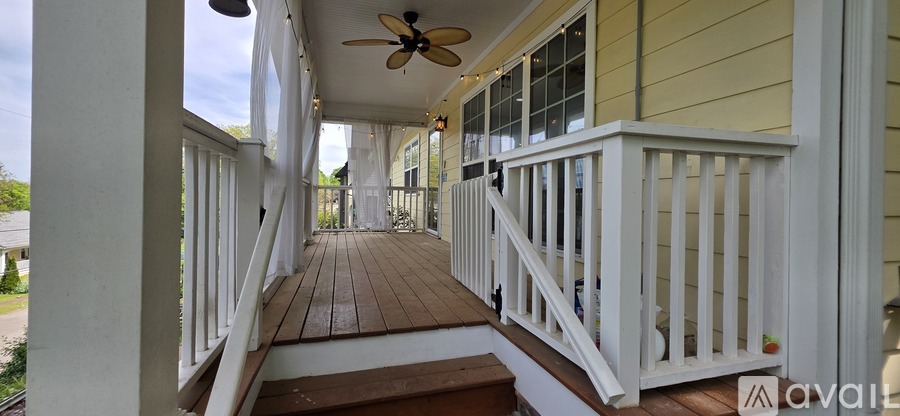 A porch with a fan and steps leading to a door.