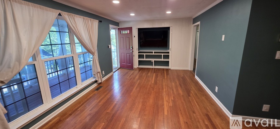 A room with wooden floors and a window with curtains.