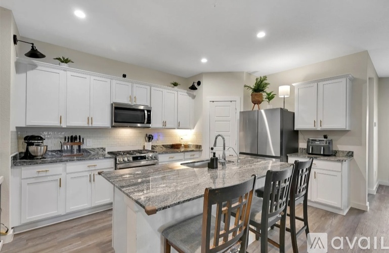A kitchen with white cabinets and a granite countertop.