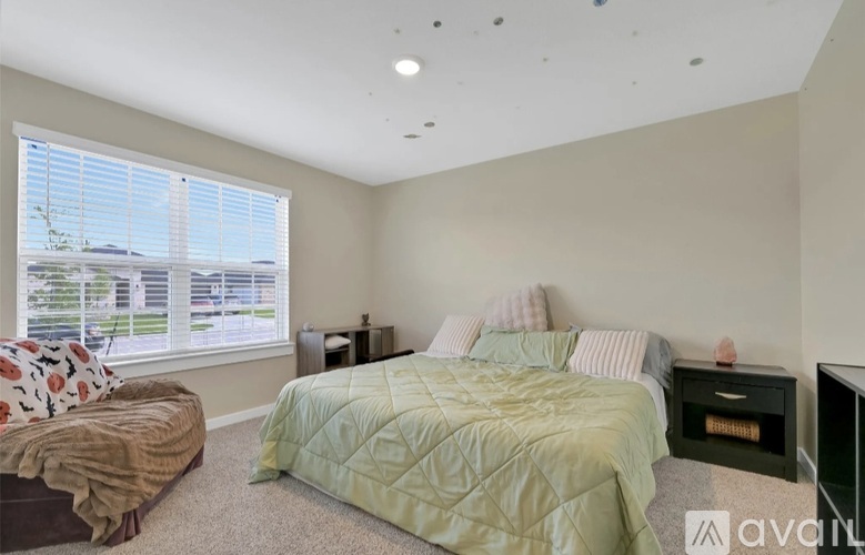 A bedroom with a large bed and a window with blinds.
