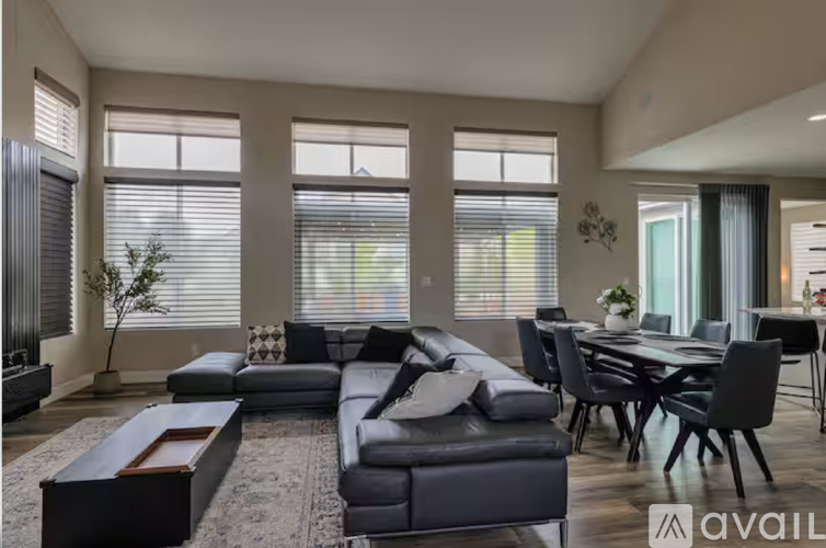 A modern living room with a black leather sofa and a dining table with chairs.
