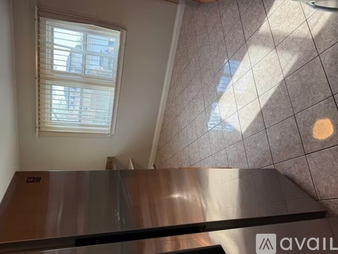 A staircase with a metal railing leads up to a window with blinds.