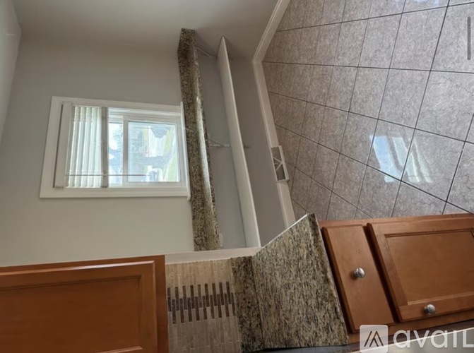 A room with a window, a curtain, and a tiled wall.