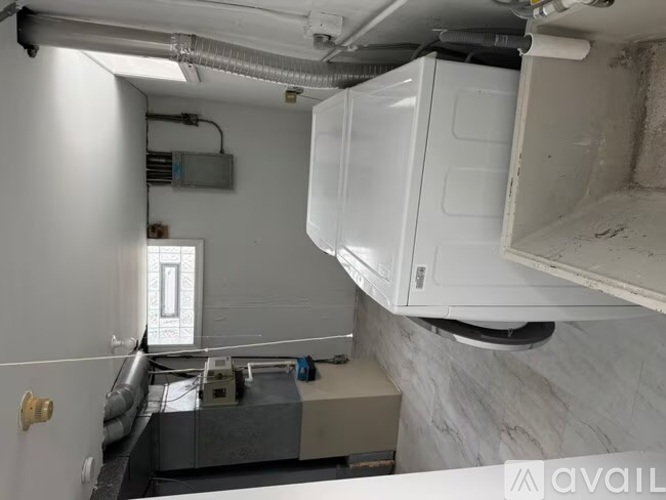 A white refrigerator is hanging from the ceiling in a room with a marble wall and a window.