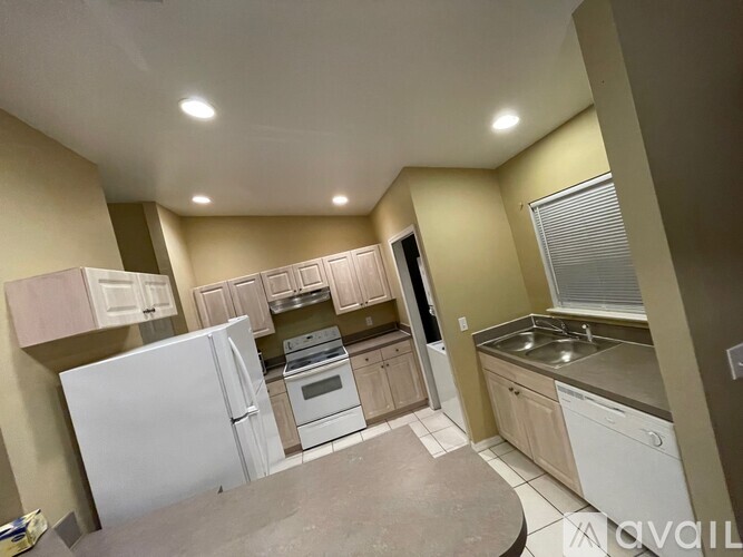 A kitchen with white appliances and wooden cabinets.