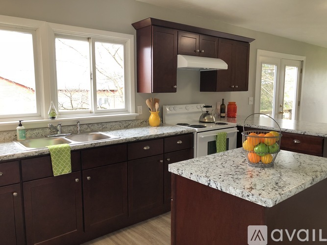 A kitchen with brown cabinets and a marble countertop.