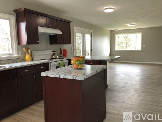 A kitchen with brown cabinets and a marble island.