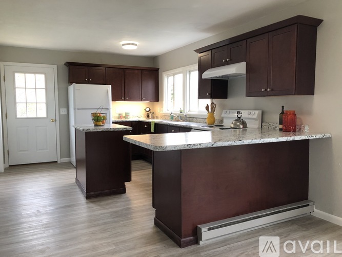A kitchen with a marble countertop and dark brown cabinets.