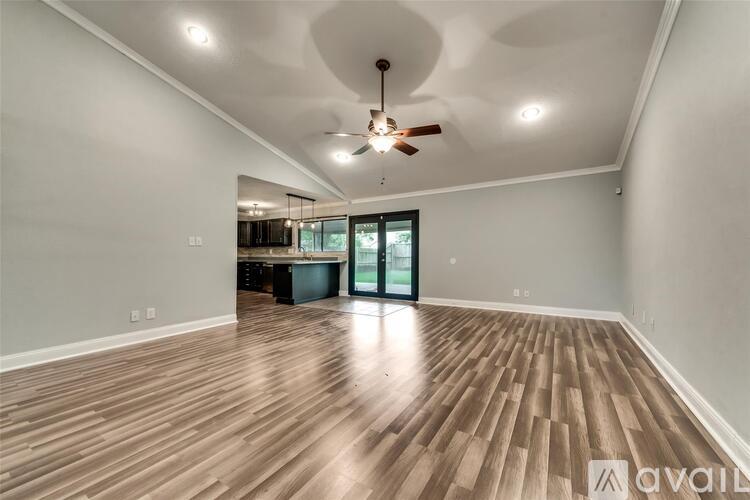 A spacious room with wooden flooring and a ceiling fan.